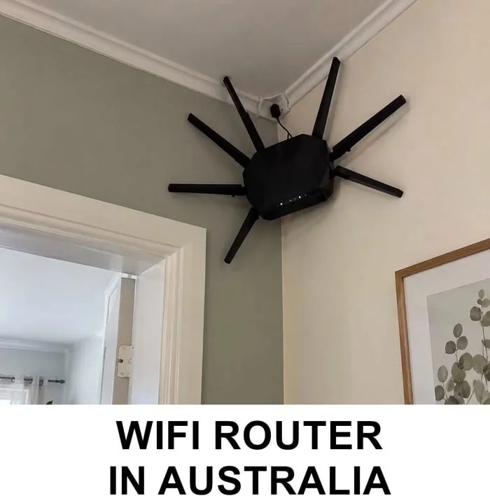 A WiFi router mounted on a ceiling corner with multiple antennas pointing outward in all directions. Text: WIFI ROUTER IN AUSTRALIA