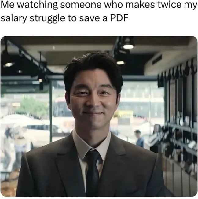 A man in business attire smiles knowingly while observing someone off-camera. Text: Me watching someone who makes twice my salary struggle to save a PDF