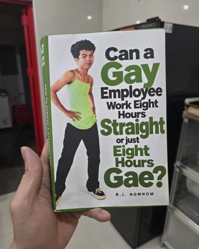 A book cover held in someone's hand featuring a person in a lime green tank top with a humorous title playing on words. Text: Can a Gay Employee Work Eight Hours Straight or just Eight Hours Gae? / B.J. NOMNOM