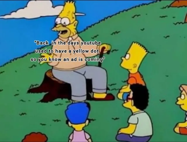 The Simpsons characters gathered outdoors, with Homer explaining an outdated YouTube feature. Text: Back in the days youtube used to have a yellow dot so you know an ad is coming