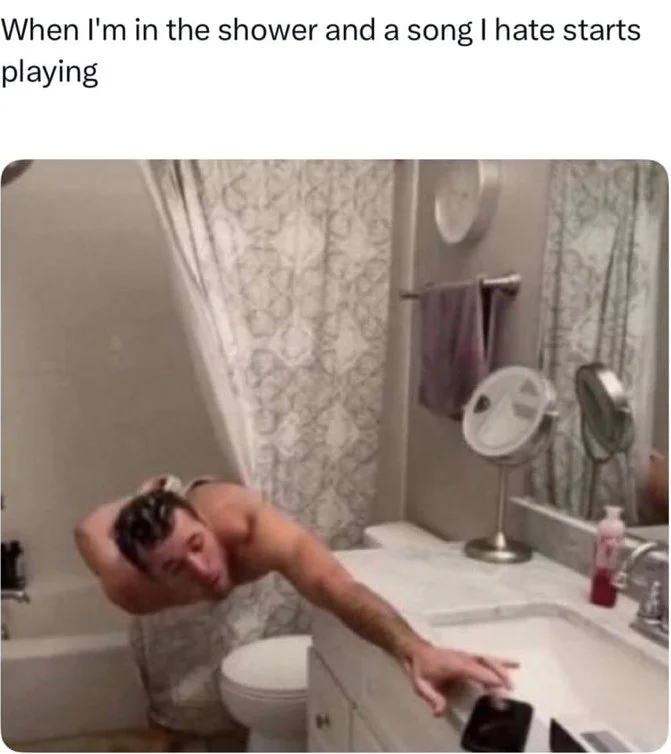 A person leaning out of a shower stall reaching desperately toward a phone on the bathroom counter. Text: When I'm in the shower and a song I hate starts playing