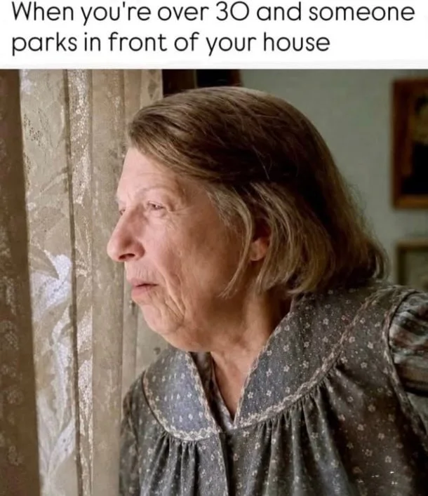An older woman peering suspiciously out a window, expressing concern about a parked car. Text: When you're over 30 and someone parks in front of your house