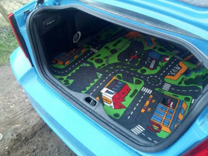 Child trap. Open car trunk displaying a colorful play mat with roads and buildings instead of typical cargo