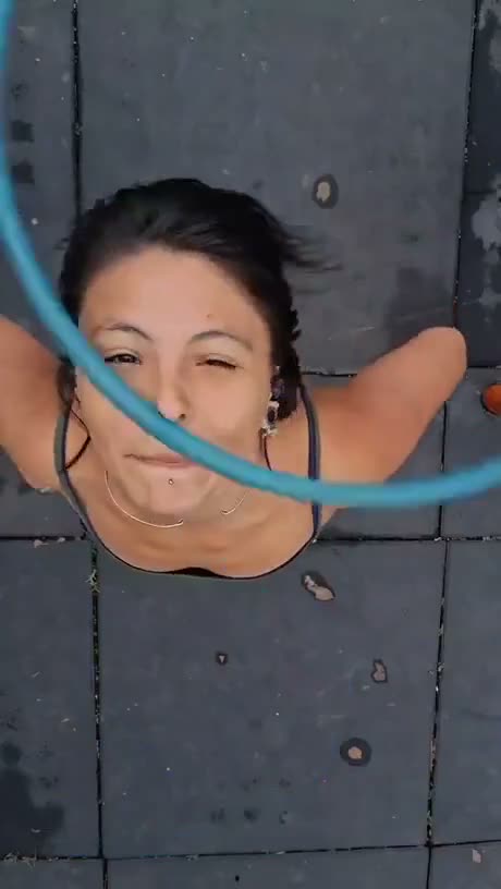 Overhead view of a person lying on dark tiles with a blue hula hoop…