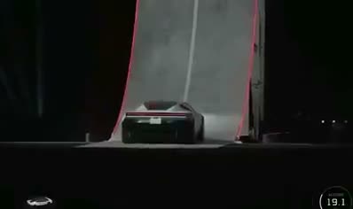 A car drives under a massive red semi-truck ramp tilted at an…