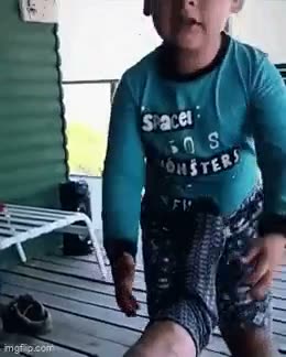 Person in teal shirt and patterned shorts standing indoors,…