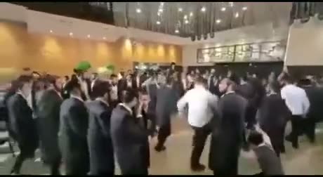Large crowd of formally dressed people gathered in an indoor venue,…