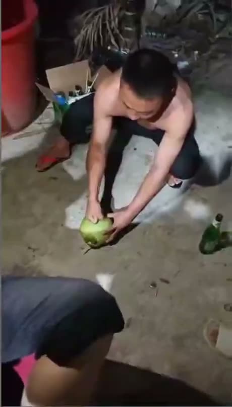 Person crouching down holding a green fruit or vegetable on concrete…