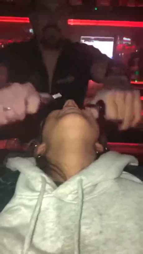Blurry video of people in a dimly lit venue with red neon lighting…