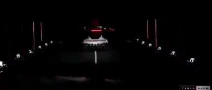 A car's dashboard view at night showing headlights on a dark road…