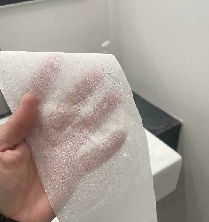 TP by Rizla. Hand holding a piece of white foam or insulation material with handprints pressed into it