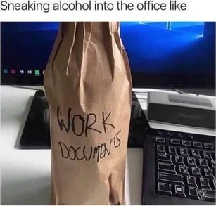 A bottle wrapped in brown paper labeled "WORK. DOCUMENTS" sits on an office desk next to a computer. Text: Sneaking alcohol into the office like / WORK. DOCUMENTS