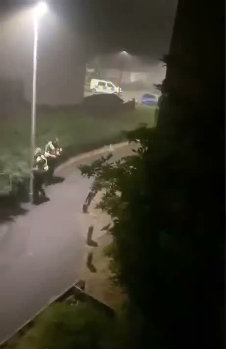 Night-time security camera footage showing a wet driveway with…