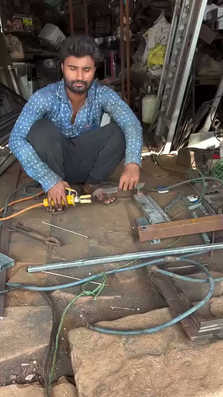 Man crouching in workshop holding tools and electrical wiring among…