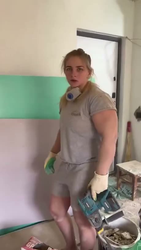 Woman in casual clothing stands in a room with green and pink…