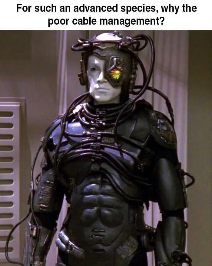 Advanced aliens, zero organizational skills. Cyberman from Doctor Who covered in tangled cables and wires, highlighting messy cable management. Text: For such an advanced species, why the poor cable management?