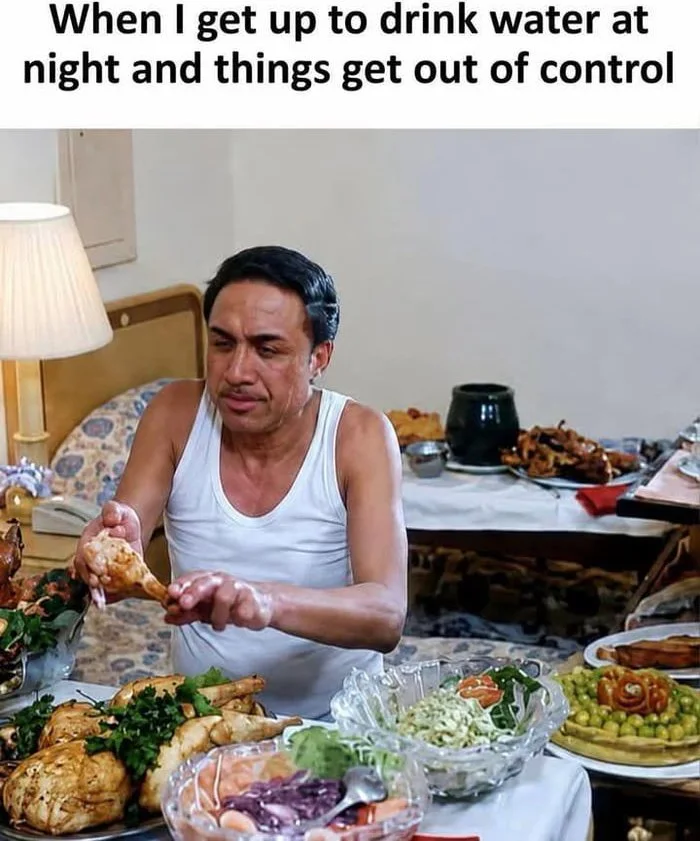 Man in tank top at table surrounded by food, eating with an exaggerated expression. Text: When I get up to drink water at night and things get out of control